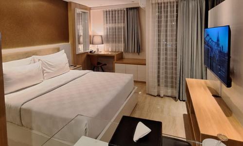 a hotel room with a large bed and a television at Swiss-Belcourt Serpong in Ciater-tengah