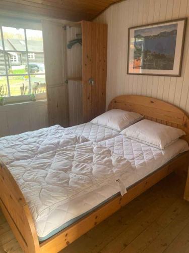 a wooden bed in a room with a window at Summer House With Shelter And Water View in Løgstør