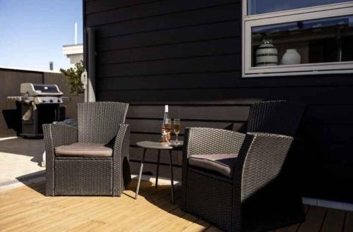 Duas cadeiras e uma mesa com um copo de vinho no pátio em Lovely Holiday Home Near Hasmark Beach em Otterup