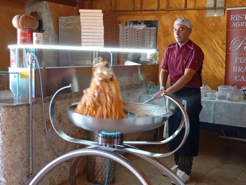 a man standing in a kitchen with a chicken in a pan at Agriturismo Il Pavone in Torre Lapillo