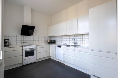 una cucina bianca con armadi bianchi e lavandino di 3 Bedroom Flat in Lovely Area a Copenaghen