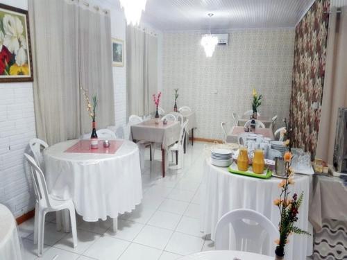 un comedor con mesas blancas y sillas blancas en Hotel Duarte, en Palmitinho
