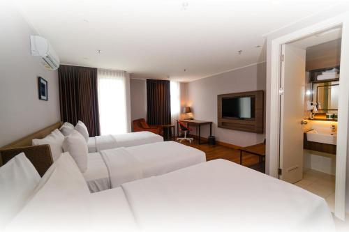 a hotel room with two beds and a television at Swiss-Belcourt Serpong in Ciater-tengah