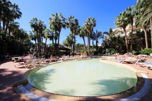 a swimming pool with lounge chairs and palm trees at Maspalomas Princess in Maspalomas