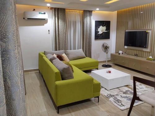 a living room with a green couch and a tv at Comfort and Style. in Benin City