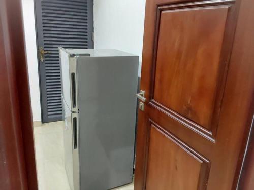 einen Kühlschrank neben einer Tür neben einer Holztür in der Unterkunft Comfort and Style. in Benin-Stadt