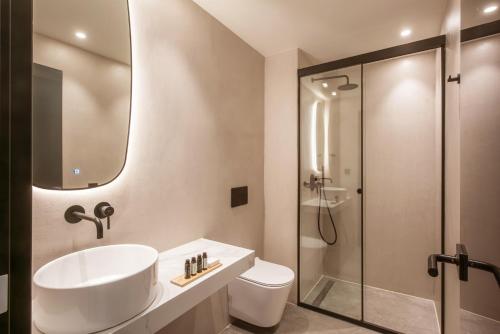 a white bathroom with a sink and a shower at Lavris City Suites in Heraklio Town