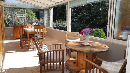 une véranda avec des tables et des chaises dans l'établissement Maison avec jardin, grande véranda, WIFI à ST QUAY-PERROS - Réf 880, à Saint-Quay-Perros