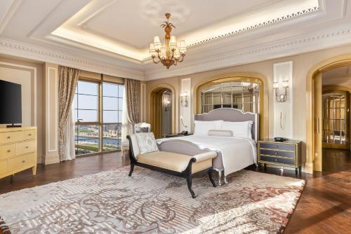 a bedroom with a bed and a chair and a chandelier at Al Habtoor Palace - Preferred Hotels & Resorts in Dubai