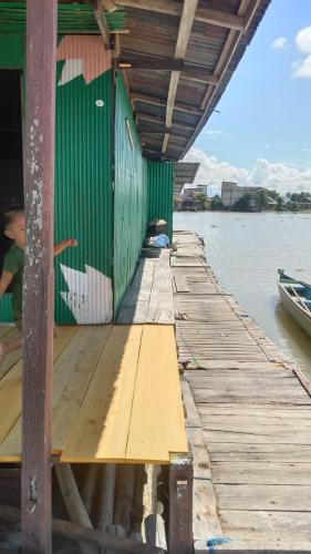 ein Holzsteg mit einem grünen Gebäude auf dem Wasser in der Unterkunft Floating house Tempe Lake 