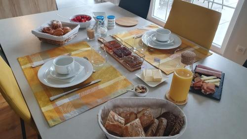 Una mesa con un desayuno de pan y pasteles. en La Maison d'Enfance, en Heimsbrunn