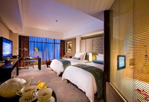a hotel room with two beds and a television at Nanyuan Universe Deluxe Hotel in Ningbo