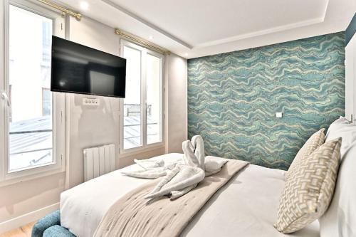 une chambre avec un grand lit avec une télévision à écran plat dans l'établissement Appartement 3 chambres Paris Sentier, à Paris