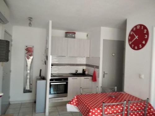 une cuisine avec une table et une horloge au mur dans l'établissement Soleil de Sète, à Sète