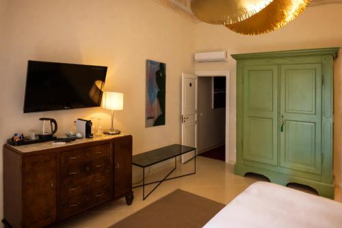 a bedroom with a green cabinet and a tv on the wall at Aria Rooms and Terrace in Noto