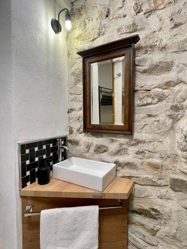 a bathroom with a sink and a mirror on a stone wall at Chambre Le 40 marches in Cucugnan