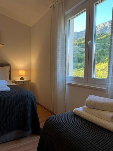 a bedroom with two beds and a large window at Apartments Curnić in Jesenice