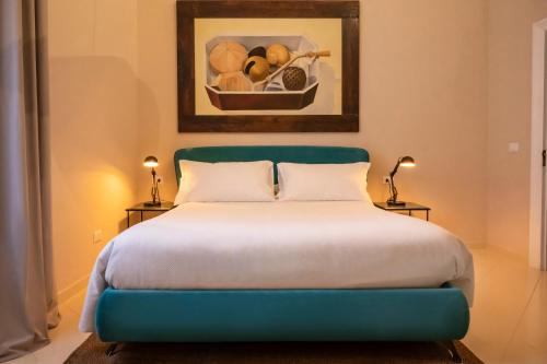 a bedroom with a blue bed with a painting on the wall at Aria Rooms and Terrace in Noto