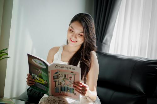 a woman sitting on a couch reading a book at Play Poshtel & Cafe' in Krabi town