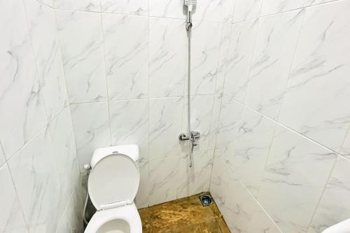 a bathroom with a toilet with white marble walls at RedDoorz @ Gunari Guest House Merek Karo in Pertibi