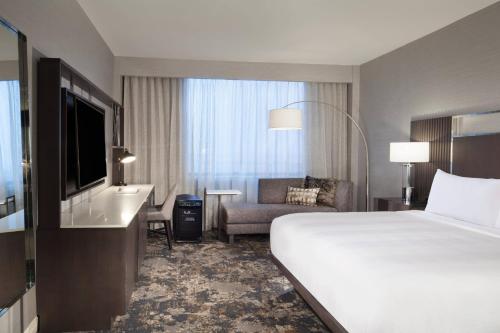 Dallas/Fort Worth Airport Marriott في ايرفينغ: غرفه فندقيه بسرير وكرسي وتلفزيون