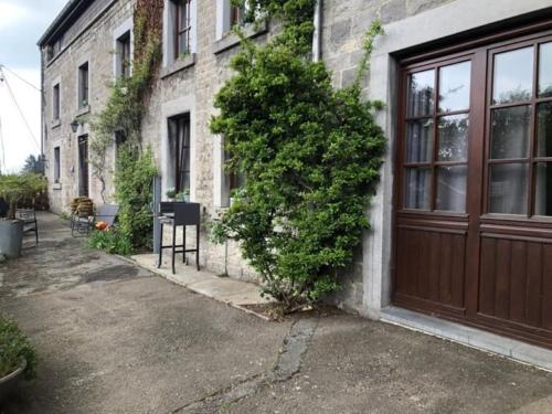 AnthisnesにあるAppartement dans une maison de charme.の木の扉と茂みのある建物