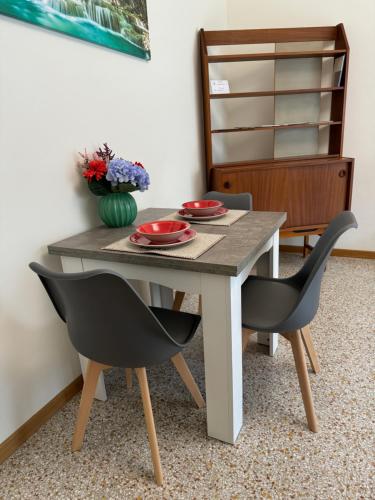a dining room table with two chairs and a vase of flowers at Rossini apartment in Sassoferrato