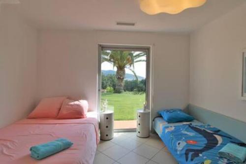 - une chambre avec 2 lits et une fenêtre avec un palmier dans l'établissement Le Domaine des vignes-Spacieuse Villa/piscine, à Hyères
