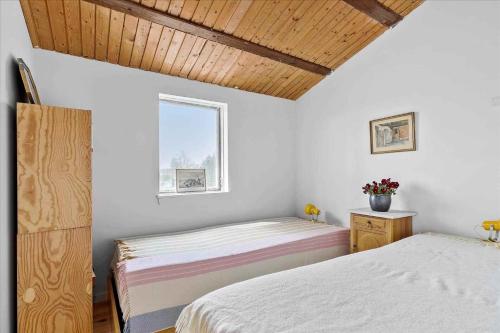 Cette chambre comprend 2 lits dans une chambre dotée de murs blancs et de plafonds en bois. dans l'établissement Summer House Brimming With Activity And Coziness,, à Nykøbing Sjælland