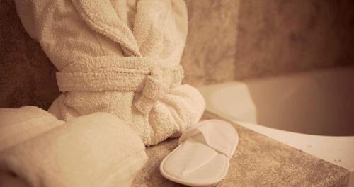 a bathroom with a towel and a sandal next to a bath tub at Hotel Vértice Chipiona Mar in Chipiona