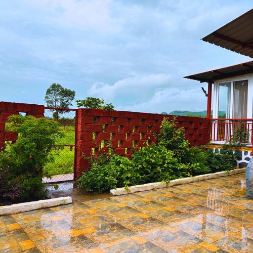 a garden with a red brick wall and bushes at Karjat Hills - Refreshing Farmstay in Karjat