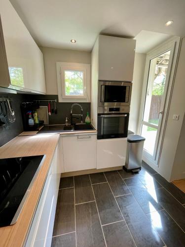 une cuisine avec un évier et une cuisinière four supérieur dans l'établissement Appartement Cosy Montigny le Bretonneux, à Montigny-le-Bretonneux