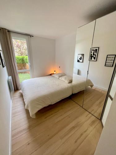 une chambre avec un grand lit et un grand miroir dans l'établissement Appartement Cosy Montigny le Bretonneux, à Montigny-le-Bretonneux
