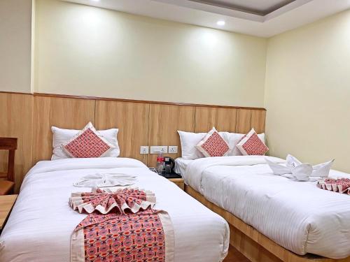two beds in a hotel room with white and red pillows at Hotel Lumbini Airport in Kathmandu