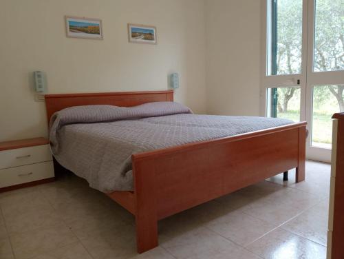- une chambre avec un lit en bois dans une pièce dotée d'une fenêtre dans l'établissement agriturismo I Gelsi Marina di Grosseto, à Marina di Grosseto