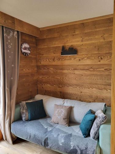 - un canapé dans une chambre dotée de murs en bois dans l'établissement Valmeinier 1800 Front de neige et piscine d été, à Valmeinier
