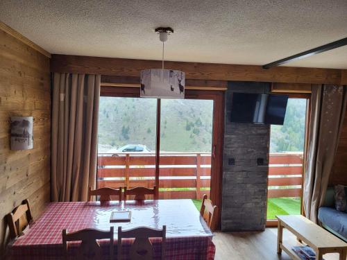 une salle à manger avec une table et une grande fenêtre dans l'établissement Valmeinier 1800 Front de neige et piscine d été, à Valmeinier