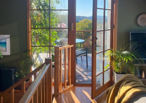 a living room with a door open to a deck at Waterfront - Bluff Beach House, Park Beach in Dodges Ferry