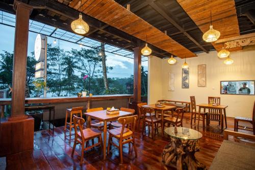 a restaurant with tables and chairs and a large window at d'kamala by Prasi in Ubud