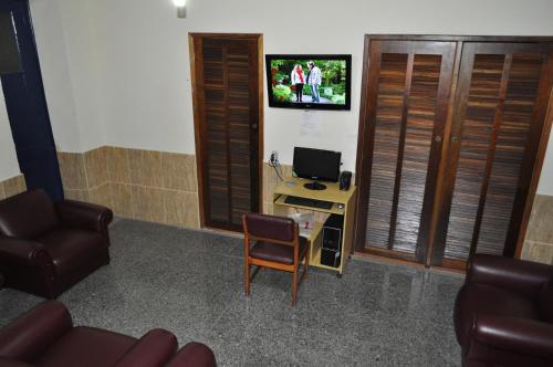 uma sala de estar com uma cadeira e uma televisão na parede em Parque Hotel no Rio de Janeiro