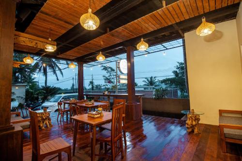 a restaurant with wooden tables and chairs and large windows at d'kamala in Ubud