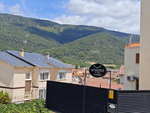 a sign in front of a building with mountains in the background at Casa del Castillo by Naturadrada in La Adrada