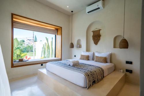 a bedroom with a large white bed and a window at Villa Rosado Canggu in Tumbak Bayuh