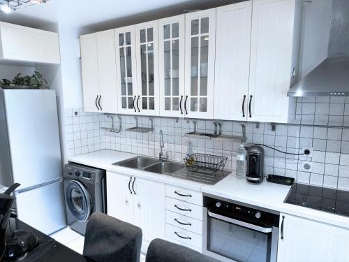 La cuisine est équipée de placards blancs, d'un évier et d'un lave-vaisselle. dans l'établissement Le jardin du stade by UTA HOUSE, à Saint-Denis