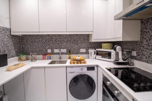 a kitchen with white cabinets and a washing machine at Prestigious Apartment on Oxford Street - 3 Bedroom 7GC in London