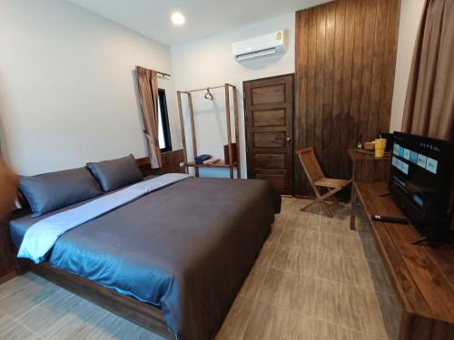 Un dormitorio con una cama, un escritorio y un televisor. en Hello Montri, en Klong Muang Beach