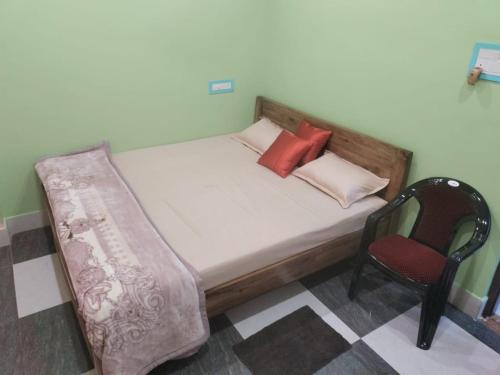 uma cama e uma cadeira num quarto em Maruti Guest House em Puri
