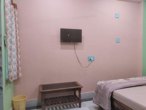 um quarto com uma cama e uma televisão na parede em Maruti Guest House em Puri