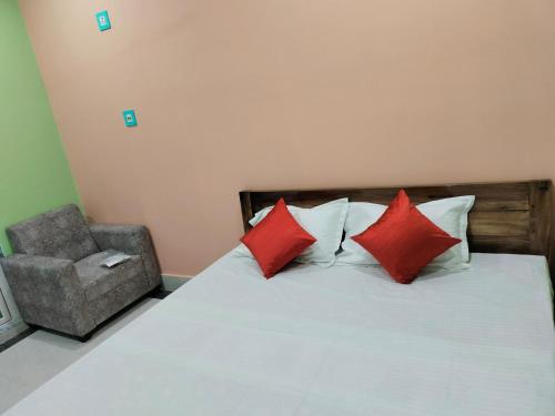 um quarto com uma cama com almofadas vermelhas e uma cadeira em Maruti Guest House em Puri