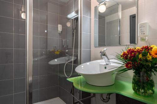 a bathroom with a sink and a vase of flowers at Zenitude Hôtel-Résidences Nantes Métropole in Nantes